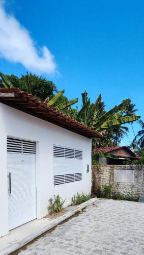 uma casa branca com duas portas de garagem e palmeiras em Casa Amarela em São Miguel dos Milagres