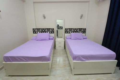 two beds in a room with purple sheets and purple pillows at Ramsses Palace in Luxor