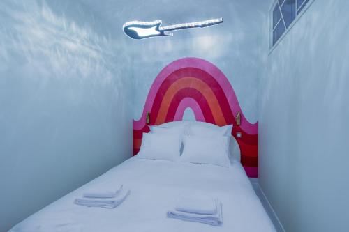une chambre avec un lit avec un arc-en-ciel peint dessus dans l'établissement Beautiful Modern Barbie flat in Paris, à Paris
