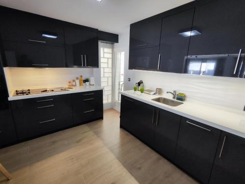 a kitchen with black cabinets and a sink at Experiencia Premium en la Esencia de Denia in Denia