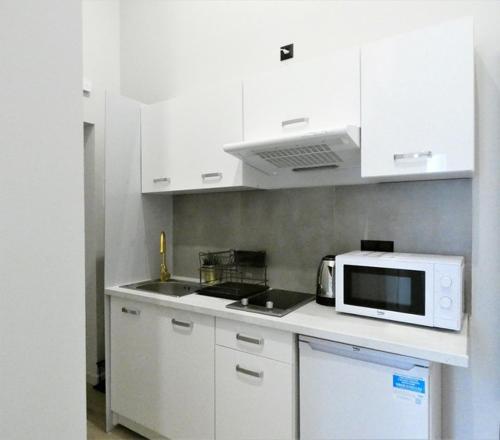 a kitchen with white cabinets and a microwave at Hola Apartamenty Legionow 2 in Łódź