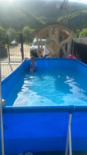 un niño en una gran piscina azul en Pensiunea Cascada Putnei, en Lepşa