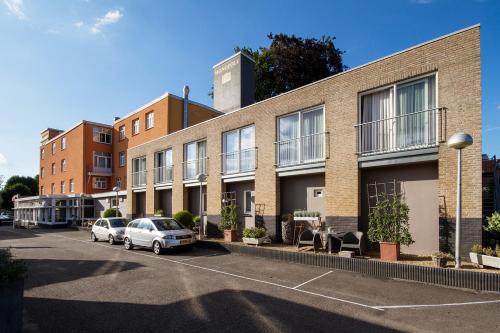 a brick building with cars parked in a parking lot at Grand Hotel Monopole in Valkenburg