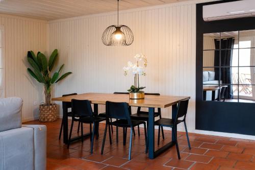 a dining room table with chairs and a vase of flowers at Caniçada House - Gerês in Vieira do Minho
