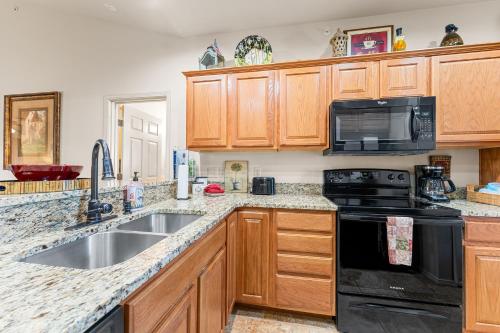 a kitchen with wooden cabinets and a sink and a stove at Ozark Comfort Condo in Branson West
