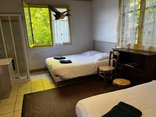 a room with two beds and a desk and two windows at Chalet au bord de l'étang 4 pers in Les Boulmiers
