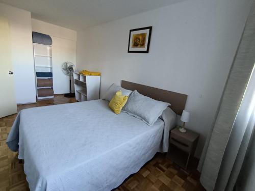 een slaapkamer met een wit bed en 2 gele kussens bij Apartamento para cuatro personas totalmente equipado in Montevideo