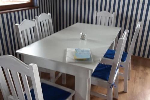 una mesa blanca y sillas con un libro. en Holiday homes for 7 people in winouj cie, en Karsibór