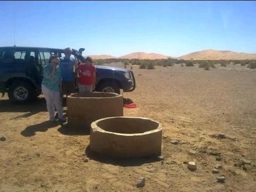 Un gruppo di persone in piedi accanto a un camion nel deserto. di GITE Take Ur time a Merzouga