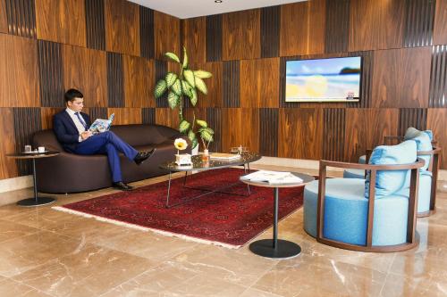 a man sitting on a couch in a living room at Fesa Business Hotel in Gebze