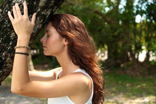 a young woman standing next to a tree at ECO CEIBA in Busque