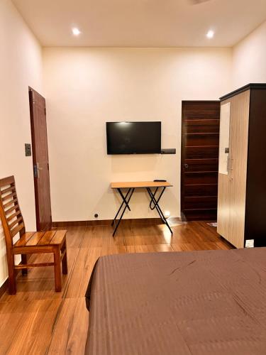 1 dormitorio con escritorio y TV en la pared en Chittattinkara Ayurvilla Traditional wellness Retreat, en Trivandrum