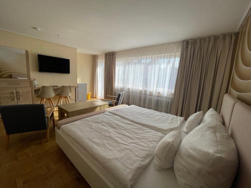 a hotel room with a bed and a desk and a window at Hotel Andrea in Crailsheim