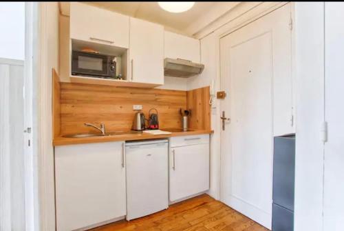 une petite cuisine avec des armoires blanches et un micro-ondes dans l'établissement Charmant deux pièces Caen centre, à Caen