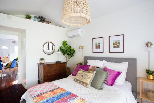 a bedroom with a bed with pink and green pillows at Stylish 2bed 2bath Culver Cottage with bicycles in Los Angeles