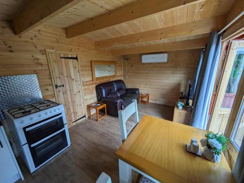 a kitchen and living room with a stove and a chair at Cosy Cabin in Stock