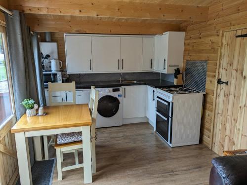 a kitchen with white cabinets and a table and a stove at Cosy Cabin in Stock