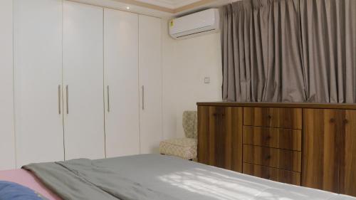 1 dormitorio con 1 cama, vestidor y silla en Palm Court en Accra