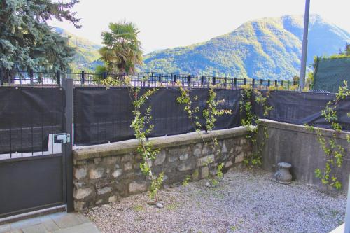a stone retaining wall with a fence and mountains in the background at The Painter's Nest with Private Lake Garden in Cima