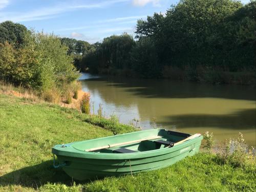 a green boat sitting on the side of a river at Cosy Cabin in Stock