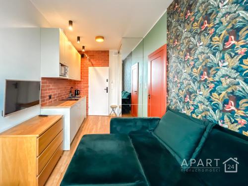 uma sala de estar com um sofá verde e uma cozinha em Biskupia Central Apartment em Gdansk