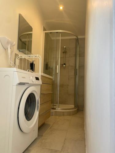 a washing machine in a bathroom with a shower at Massy Appart Hotel in Massy