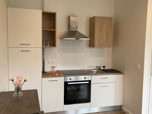 a kitchen with white cabinets and a stove top oven at Massy Appart Hotel in Massy