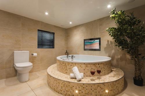 a bathroom with a tub and a toilet at Aphrodites Group - Luxury Hot Tub Suites in Central Lake District! in Bowness-on-Windermere