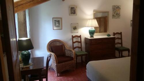 1 dormitorio con cama, silla y espejo en Domaine du Paraïs B&B, en Sospel