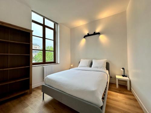 een witte slaapkamer met een bed en een raam bij Le Nid de Saint André in Lille