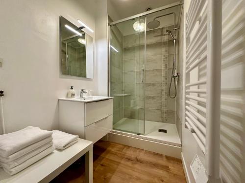 een witte badkamer met een douche en een wastafel bij Le Nid de Saint André in Lille
