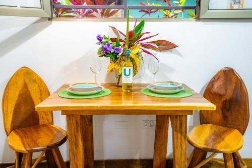 a wooden table with two chairs and a vase of flowers at Casitas Del Rio Riverfront Jungle Beach Vacation in Uvita