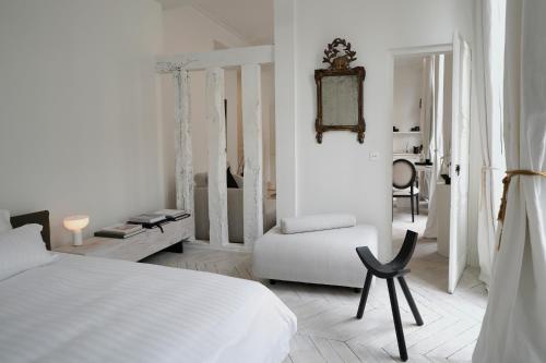 une chambre blanche avec un lit et une chaise dans l'établissement Opalin, à Paris