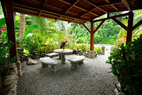 un patio con una mesa y bancos bajo un pabellón en Casitas Del Rio Riverfront Jungle Beach Vacation, en Uvita