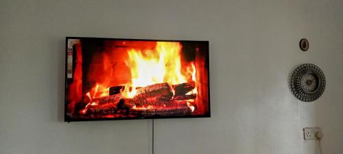 a tv hanging on a wall with a fire in it at COZY COTTAGE® 