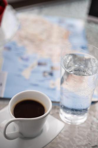 a cup of coffee and a glass of water on a table at Sea and sun in Kalamitsa