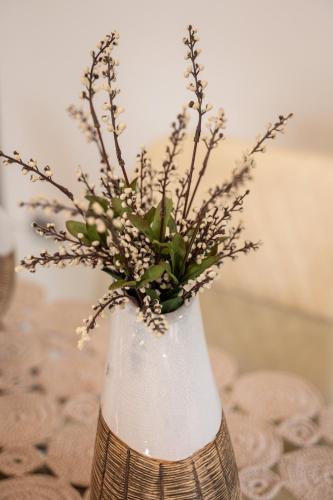a white vase with some flowers in it at Sea and sun in Kalamitsa