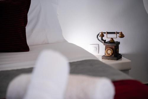 a bed with a lamp and a clock on a night stand at Sea and sun in Kalamitsa
