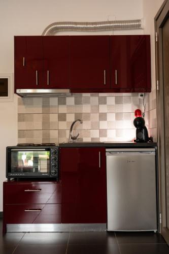 a kitchen with red cabinets and a microwave at Sea and sun in Kalamitsa