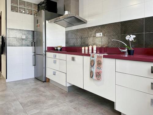 una cocina con armarios blancos y encimeras rojas en Brisa Marina, en Las Negras