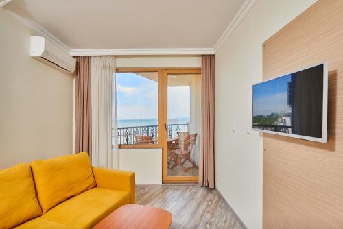 a living room with a couch and a balcony at Crotiria Beach - Aparthotel in Pomorie