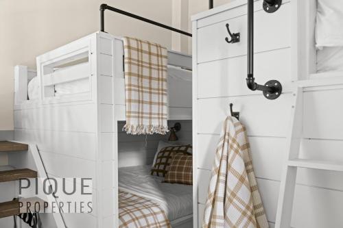 a childs bunk bed in a white room with a bed in it at Mountain Loft Retreat, Heated Pool & Hot Tub, UG Parking, Balcony, WiFi! in Canmore
