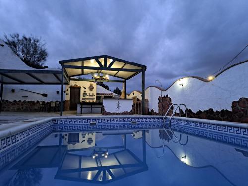 a swimming pool with a gazebo next to a pool at CASA CUEVA LOS HONORIOS in Cortes de Baza