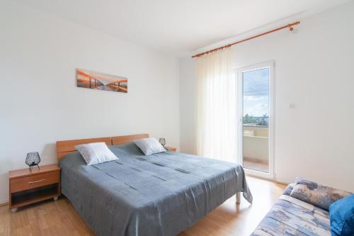 a bedroom with a bed and a couch and a window at Apartments Josipa in Mandre