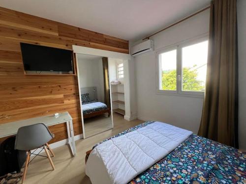 - une chambre avec un lit et une télévision murale dans l'établissement GITE PEI LA VANILLE "Studio Cosy en Bord de Nature", à Sainte-Suzanne