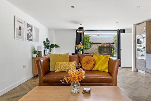 una sala de estar con un sofá de cuero marrón con almohadas amarillas en Peterswell Holiday Cottage, en Houston