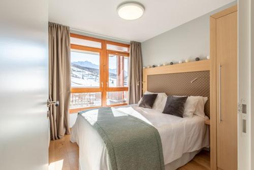 - une chambre avec un lit et une grande fenêtre dans l'établissement Les Arcs 1800 : Appartement ski in/out avec spa, à Bourg-Saint-Maurice