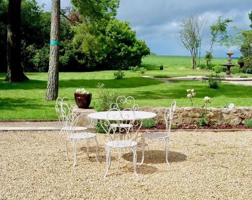 une table et des chaises blanches installées dans un parc dans l'établissement Château Déhès Gazaupouy 1 chambre d'hôte et 1 Gite, à Gazaupouy