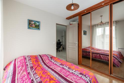 une chambre avec un lit et un miroir dans l'établissement Charmant appartement Villemomble, à Villemomble