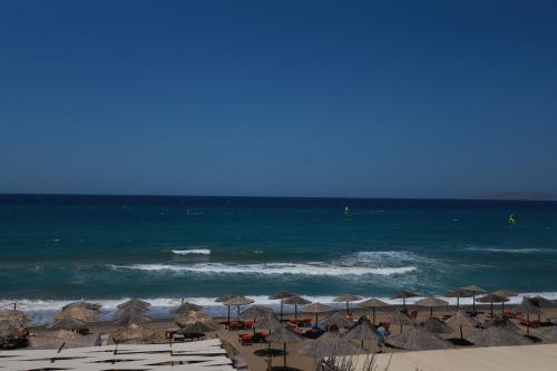 a beach with umbrellas and chairs and the ocean at Tropical Beach A in Amoudara Herakliou